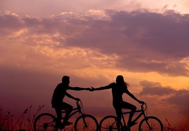 woman on bike reaching for man's hand behind her also on bike