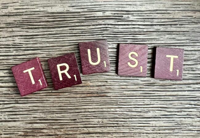 trust spelled with wooden letter blocks on a table